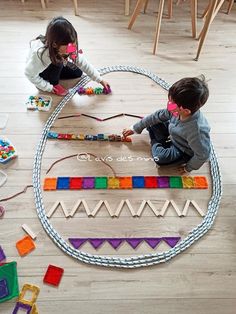 two children playing with toys on the floor in front of them, one child is holding a string