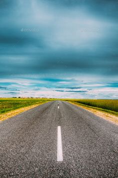 an empty road in the middle of nowhere with blue sky and clouds above - stock photo - images