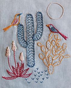 some embroidery work on a piece of cloth with birds and cactuses in the background