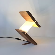 a wooden table lamp with a white light on the top and an electric cord attached to it