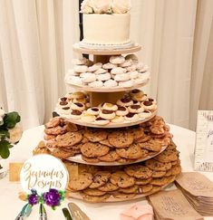 a cake and cookies are stacked on top of each other at a table with flowers