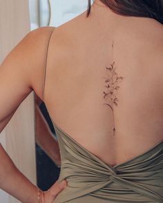 the back of a woman's dress with a flower tattoo on her lower back