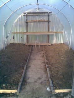 the inside of a greenhouse with plants growing in it and some dirt on the ground