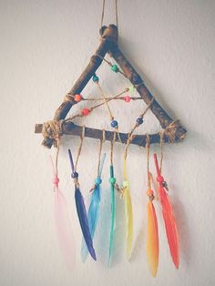 a colorful dream catcher hanging on the wall with feathers attached to it's sides