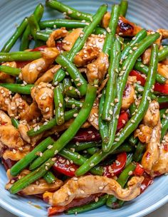 chicken and green beans with sesame seeds in a blue bowl on a white tablecloth