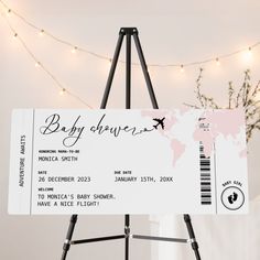 a baby shower ticket sitting on top of a easel in front of a map