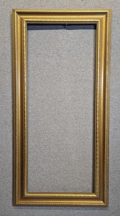 an old gold frame hanging on the wall with a gray carpet in front of it