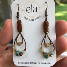 a pair of earrings is shown in front of a card with the name ela on it