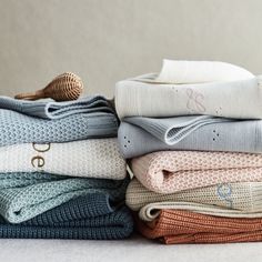 several folded sweaters stacked on top of each other in different colors and sizes,