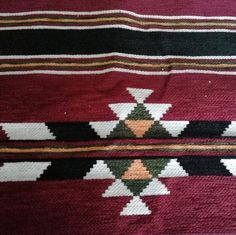 a red blanket with white, black, and orange designs on it's edges