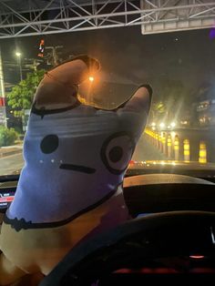 a stuffed animal is sitting in the driver's seat of a car at night