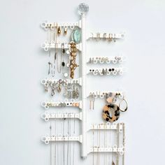 a white wall mounted jewelry rack with lots of necklaces and rings on it's sides