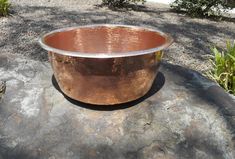 a large metal bowl sitting on top of a rock