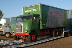 a green freight truck on a flatbed trailer