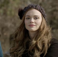 a woman with long hair wearing a knitted headband and looking at the camera