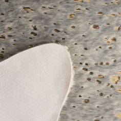 an animal's fur with brown spots on it and some white material in the background