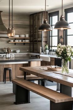 a kitchen with wooden table and benches in front of the counter top, lights hanging over it