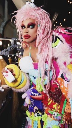 a woman with pink hair and makeup is dressed up as a drag queen holding a banana