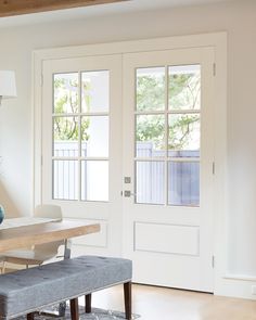 a dining room table and bench in front of a white door with glass panes