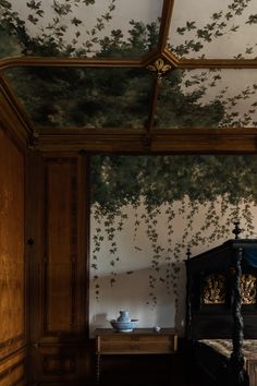 a bed room with a neatly made bed next to a wall covered in green leaves