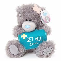 a gray teddy bear holding a blue sign with the words get well soon on it