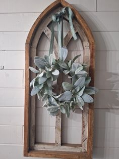 a wreath hanging on the side of a wall next to a wooden frame with leaves