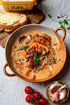 a bowl filled with soup next to bread and tomatoes