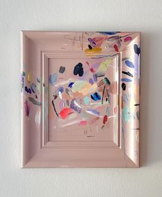 an abstract painting is hanging on the wall in front of a white wall with a pink frame