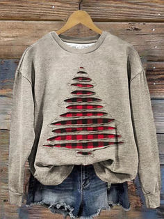 a sweater with a christmas tree on it hanging from a hanger in front of a wooden wall