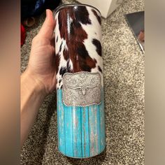 a hand holding a blue and white can with cow print on the inside, sitting on a carpeted floor