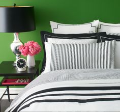 a bed with black and white striped comforter next to a table with pink flowers