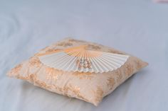 a decorative pillow with a fan on it's front end, sitting on a bed