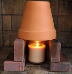 a lit candle sitting in front of a brick fireplace with bricks around it and a lamp on top