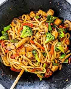 a wok filled with stir fry noodles and vegetables