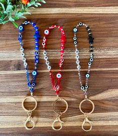 three evil eye key chains on top of a wooden table next to an orange flower