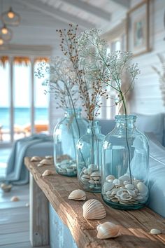 three vases filled with flowers and seashells on a table