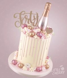 a white cake topped with a bottle of champagne and some pink candies on top