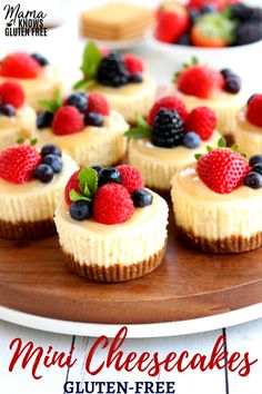 mini cheesecakes with fresh berries and blueberries are on a wooden platter