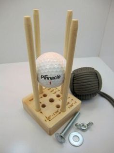 a golf ball on a wooden stand with screws and nuts next to the hole