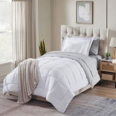 a bed with white comforter and pillows in a room