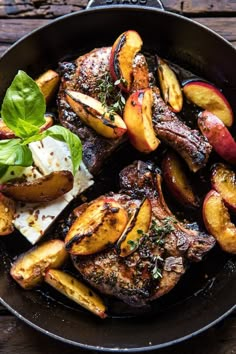 a skillet filled with meat and potatoes on top of a wooden table next to a fork