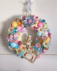 a colorful wreath hanging from the side of a wall with an ornament on it