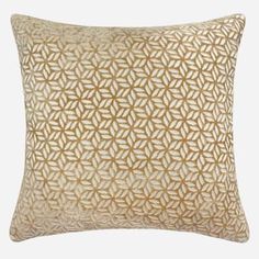 a gold and white pillow with an intricate design on the front, along with a beige background