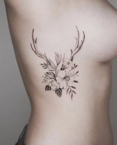 a woman's stomach with flowers and antlers on her side, while she is wearing