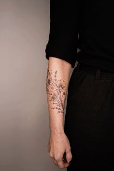 a person with a flower tattoo on their left arm and the other hand is holding something