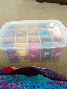 a plastic container filled with lots of crafting supplies on top of a carpeted floor