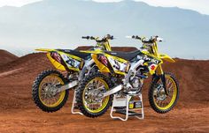 two yellow dirt bikes parked on top of each other