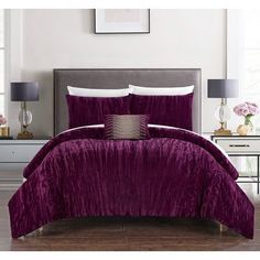 a bed with purple comforter and pillows