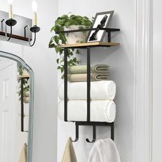 towels are stacked on a shelf in front of a mirror and hanging from the wall