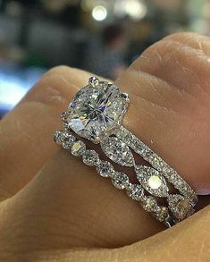 a close up of a person's hand holding a diamond ring